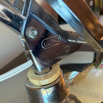 Sale Photo Thumbnail #4: Close-up detail of a vintage Luxo chrome drafting lamp mechanism showing the embossed brand logo and articulated base connection.