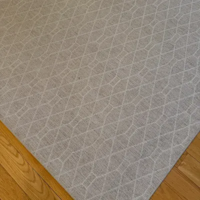 Sale Photo Thumbnail #13: Contemporary area rug in a neutral beige woven fabric featuring a subtle geometric lattice pattern, placed on a hardwood floor.