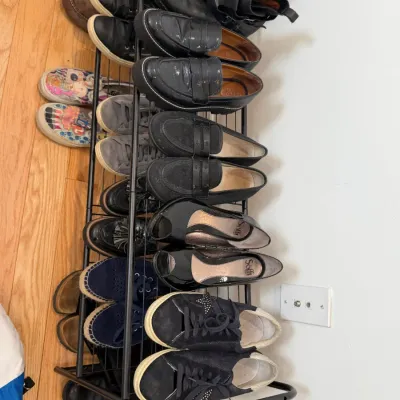 Sale Photo Thumbnail #55: Black metal shoe rack filled with various styles of women's shoes, including loafers, boots, sneakers, and heels.