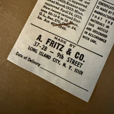 Sale Photo Thumbnail #46: Vintage manufacturer compliance tag for A. Fritz & Co. attached to an upholstered furniture item.
