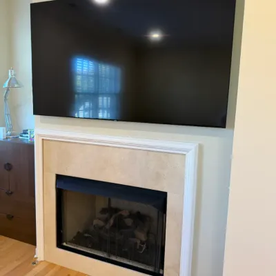 Sale Photo Thumbnail #37: Wall-mounted large flat-screen television positioned above a modern built-in gas fireplace with marble surround.
