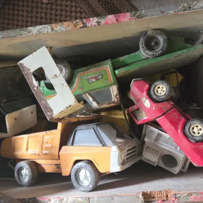 Sale Photo Thumbnail #16: Collection of vintage pressed steel toy trucks, including Tonka and Nylint brands, stored inside a wooden chest.