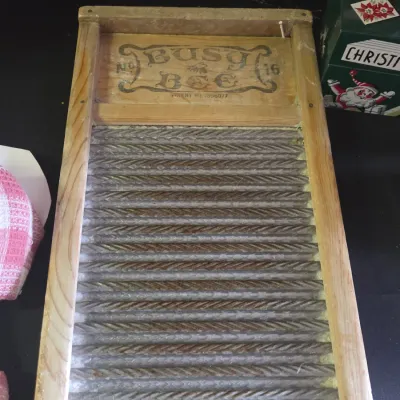 Sale Photo Thumbnail #39: Vintage Busy Bee No. 16 glass washboard set in a wooden frame with printed brand graphic at the top.