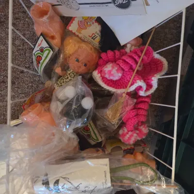 Sale Photo Thumbnail #133: Wire basket filled with vintage craft supplies, doll parts, instructions, and handmade crocheted accessories.