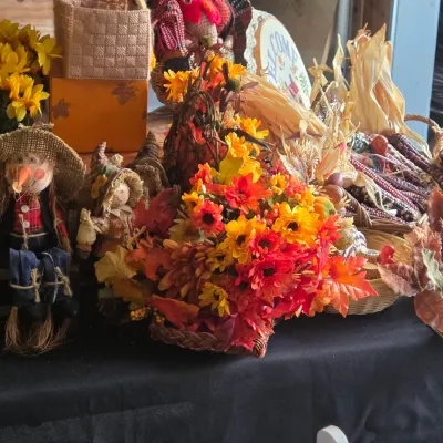 Sale Photo Thumbnail #23: Collection of autumn and Thanksgiving decor, including scarecrow figurines, faux floral arrangements, and decorative dried Indian corn in baskets.