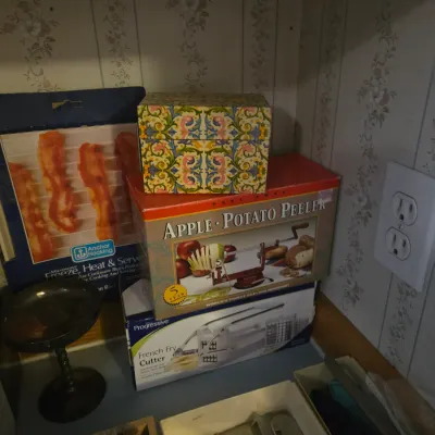 Sale Photo Thumbnail #95: Collection of vintage boxed kitchen items including an Apple & Potato Peeler, Progressive French Fry Cutter, Anchor Hocking Microwave Freeze Heat & Serve rack, and a floral trinket box.