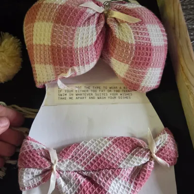 Sale Photo Thumbnail #40: Novelty bikini-shaped dishcloth set made from pink and white gingham waffle-weave towels mounted on cardboard with a printed poem.