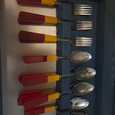 Sale Photo Thumbnail #111: Vintage Bakelite flatware set with two-tone red and butterscotch handles, housed in a fabric-lined storage case.