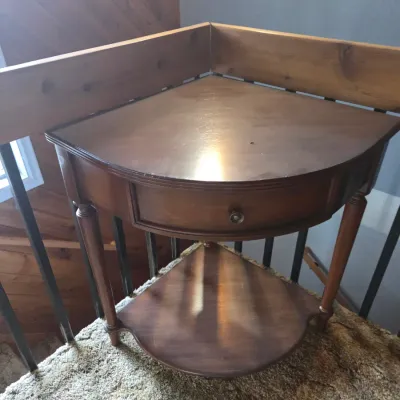 Sale Photo Thumbnail #84: Traditional wooden corner side table with a single drawer and a lower display shelf. Features fluted turned legs and minor surface wear on the tabletop.