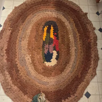 Sale Photo Thumbnail #140: Handcrafted oval braided rag rug featuring concentric earth tones with a colorful central floral motif.