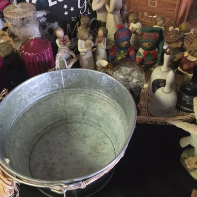 Sale Photo Thumbnail #32: Large galvanized metal bucket with a wire handle, surrounded by Willow Tree figurines, decorative bells, and plush holiday bear decor.