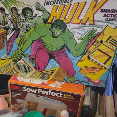 Sale Photo Thumbnail #37: Vintage 1979 Ideal 'The Incredible Hulk Smash Action Game' in original box, displayed alongside a vintage Sew Perfect toy sewing machine and other collectible goods.