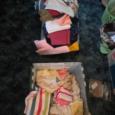 Sale Photo Thumbnail #131: Clear plastic storage totes filled with sorted crafting fabrics, vintage crocheted doilies, and various textile remnants.