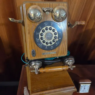 Sale Photo Thumbnail #141: Vintage-style Crosley Limited Edition wooden wall-mount telephone featuring brass gongs, rotary dial, and hand crank.