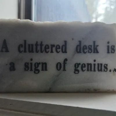 Sale Photo Thumbnail #12: Vintage white marble paperweight featuring printed black lettering that reads "A cluttered desk is a sign of genius."