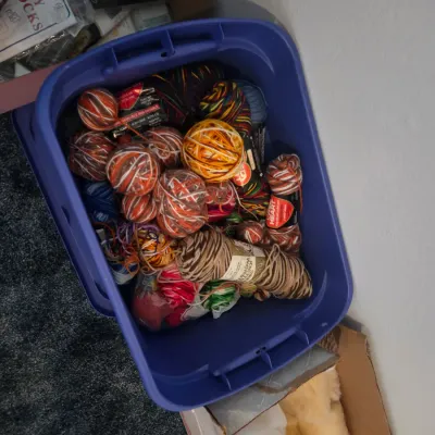 Sale Photo Thumbnail #125: Purple plastic storage tub filled with various skeins and balls of colorful knitting and crochet yarn.