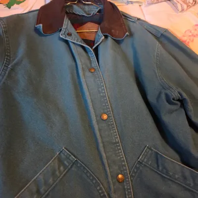 Sale Photo Thumbnail #122: Vintage Woolrich teal canvas chore jacket featuring a brown leather collar and snap-front closure.