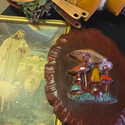 Sale Photo Thumbnail #43: Vintage 1970s resin mushroom wall plaque alongside a framed Warner Sallman print of Jesus as the Good Shepherd and copper-colored frying pans.