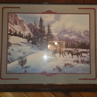 Sale Photo Thumbnail #69: Framed Western landscape art print depicting a rider and pack horse in a snowy mountain setting, housed in a stepped mat and dark wood frame.