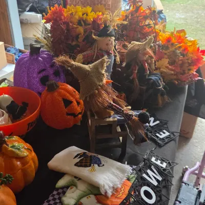 Sale Photo Thumbnail #34: Collection of autumn and Halloween decor, including glittery jack-o'-lanterns, scarecrow dolls, ceramic pumpkins, embroidered hand towels, and floral arrangements.