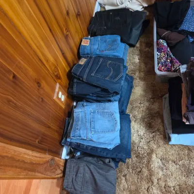 Sale Photo Thumbnail #142: Stack of folded denim jeans and trousers on the floor, including brands like Levi's.