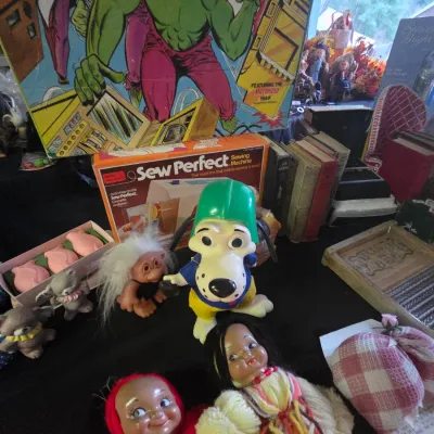 Sale Photo Thumbnail #27: Assortment of vintage toys and collectables including an Incredible Hulk board game, a Sew Perfect toy sewing machine, various dolls, and a cartoon dog figure.