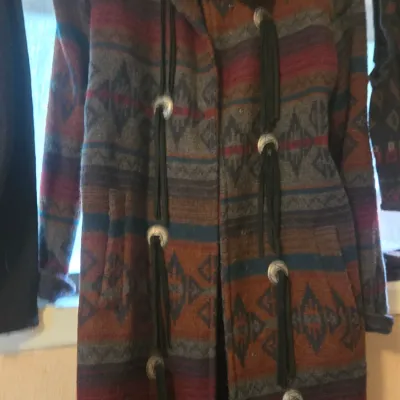 Sale Photo Thumbnail #64: Southwestern-style full-length wool coat featuring a geometric tribal pattern in earth tones, detailed with silver concho buttons and black leather fringe tassels.