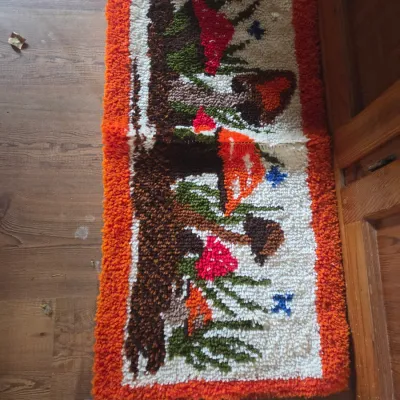 Sale Photo Thumbnail #154: Vintage 1970s latch-hook shag rug featuring a mushroom forest design with an orange border.