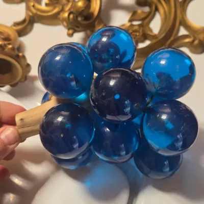 Sale Photo Thumbnail #50: Vintage mid-century blue Lucite acrylic resin grape cluster featuring translucent orb grapes attached to a natural wood stem.