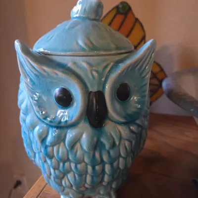Sale Photo Thumbnail #104: Light blue glazed ceramic owl-shaped cookie jar featuring a crackle finish and black painted eyes and beak.