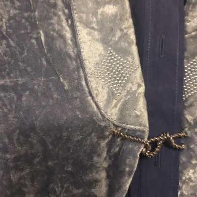 Sale Photo Thumbnail #139: Detail of a vintage crushed velvet jacket or robe featuring rhinestone-embellished trim and a decorative metallic cord closure.