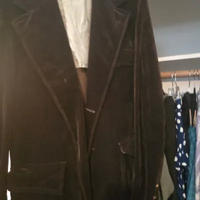 Sale Photo Thumbnail #124: Vintage dark brown corduroy or velvet blazer featuring wide notched lapels and front flap pockets, hanging in a closet.