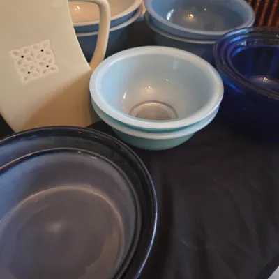 Sale Photo Thumbnail #116: Collection of mid-century ceramic and glass kitchenware, including a cream pitcher with embossed details and various blue mixing bowls.