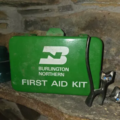 Sale Photo Thumbnail #71: Vintage Burlington Northern green metal first aid kit box, shown alongside a small black cat ring holder figurine.