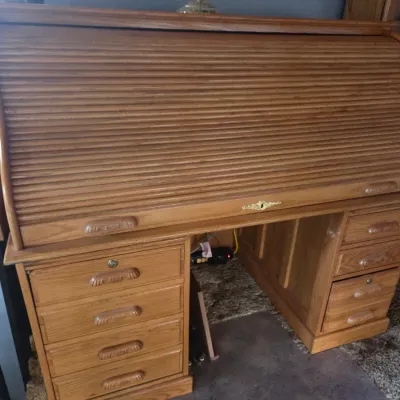 Sale Photo Thumbnail #83: Traditional oak roll-top desk featuring a tambour door, brass keyhole detail, and multiple side drawers.