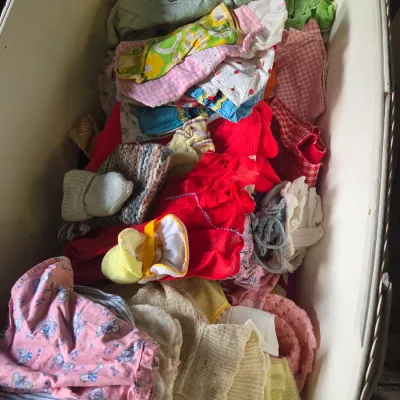 Sale Photo Thumbnail #22: Large collection of vintage baby clothes and knitted accessories stored inside a white bassinet or chest, featuring various mid-century patterns, colors, and styles.