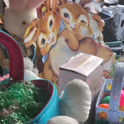 Sale Photo Thumbnail #24: Collection of vintage Easter decorations, featuring a cardboard bunny cutout, plush rabbits, woven baskets, and plastic eggs.