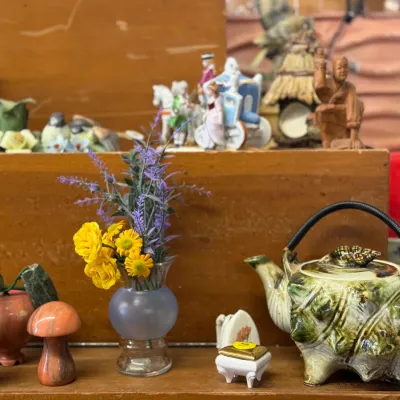 Sale Photo Thumbnail #26: Collection of decorative collectibles, including a conch shell teapot, carved stone mushrooms, artificial flower arrangement in a glass vase, and ceramic figurines.