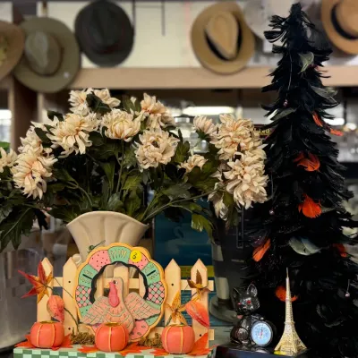 Sale Photo Thumbnail #29: Assortment of autumn and Halloween decor items, including a faux chrysanthemum arrangement, a wooden turkey fence display, a black feather tree, and a miniature Eiffel Tower statuette.