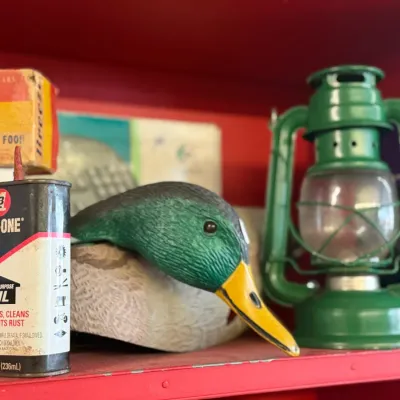 Sale Photo Thumbnail #14: Vintage shelf assortment featuring an 8 oz vintage 3-In-One oil can, a mallard duck decoy, and a green painted hurricane oil lantern.