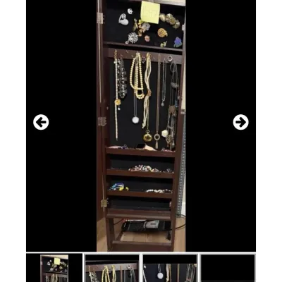 Sale Photo Thumbnail #37: Tall dark wood armoire jewelry cabinet filled with assorted costume jewelry including necklaces, brooches, and rings.