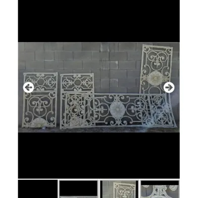 Collection of ornate, white-painted wrought iron gate or railing panels featuring intricate scrollwork and central medallion motifs.