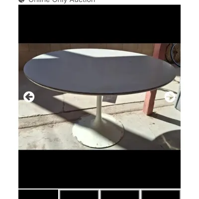 Sale Photo Thumbnail #61: Mid-century modern round tulip dining table featuring a white laminate top and pedestal base, showing wear and paint loss on the base.