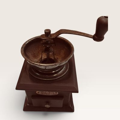Vintage-style manual coffee grinder featuring a dark wood base, cast iron hopper with hand crank, and a small grounds collection drawer.