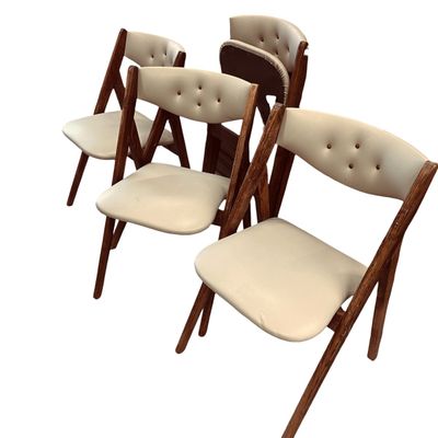 Set of mid-century folding chairs featuring dark wooden frames and cream vinyl upholstered seats with button-tufted backrests.