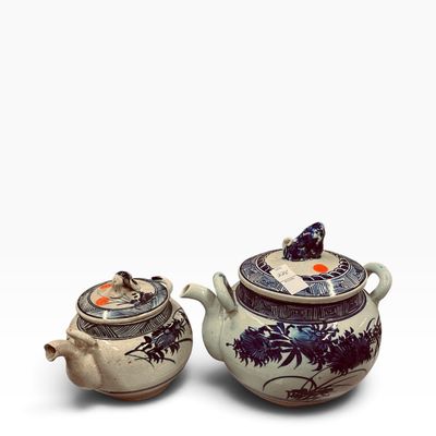 Pair of antique Asian blue and white glazed ceramic teapots with hand-painted floral motifs and sculpted foo dog lid finials.