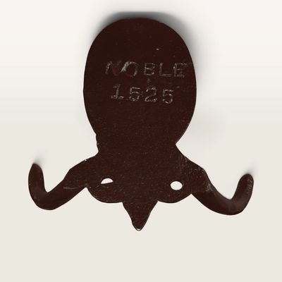 Vintage dark brown cast iron wall hook featuring a decorative crest stamped with 'NOBLE 1525'.