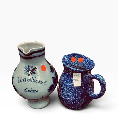 Pair of vintage ceramic pitchers, including a light blue German Bembel stoneware cider pitcher and a cobalt blue sponge-painted pitcher.
