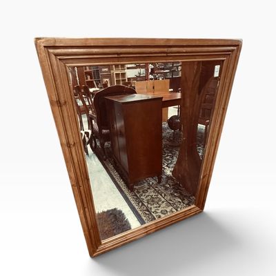 Rustic trapezoidal wall mirror with a natural light wood molded frame.