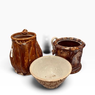 Trio of antique Rockingham glaze earthenware pottery pieces, including a spatter-glazed mixing bowl and two molded brown glaze crocks...